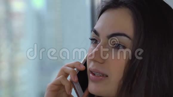 漂亮的黑发美女戴着牙套在电话特写镜头上说话视频的预览图