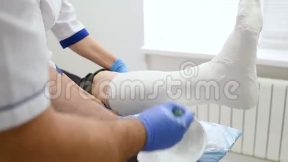 医生创伤学家在病人的腿上贴了一块石膏视频的预览图