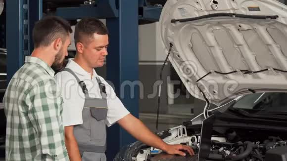 汽车修理工和他的客户在汽车服务站握手视频的预览图