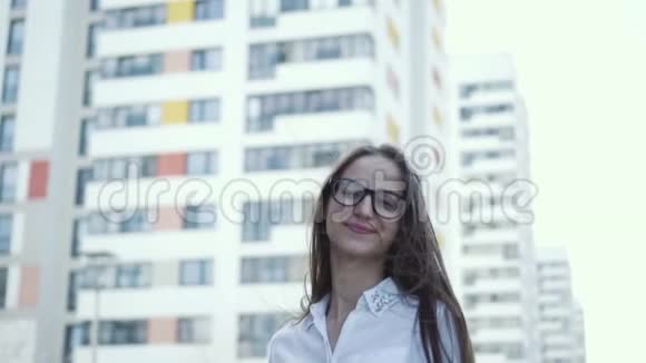 一个可爱的女孩站在城市背景上穿着商务服头发随风而动慢节奏视频的预览图