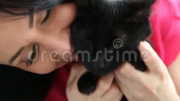 对宠物的爱美丽的黑发女孩和一只黑猫正在家里的床上放松视频的预览图