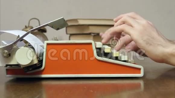 男人手拿着书在桌子上用红色复古打字机打字视频的预览图