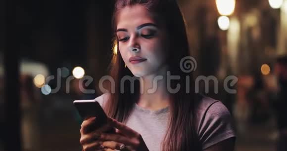 年轻迷人的女人在夜城的街道上使用手机妇女使用手机进行商务交流视频的预览图