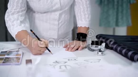一个女人的手像一个女裁缝主人她的手上画了一幅衣服的草图视频的预览图