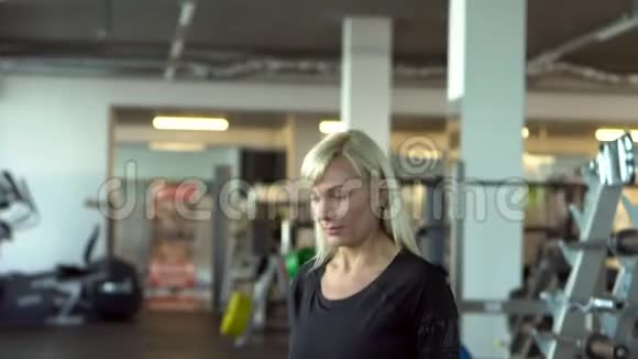 在健身房里蹲着哑铃的年轻女子视频的预览图