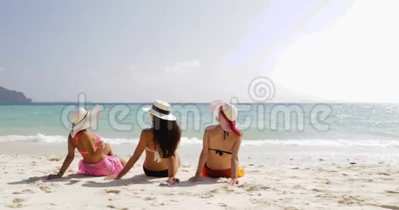 后景三个穿比基尼和草帽的女孩在海滩上享受日光浴女游客在暑假视频的预览图