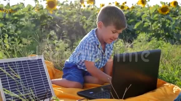 现代童年快乐的孩子使用太阳能电池充电笔记本电脑背景领域向日葵孩子看着视频的预览图