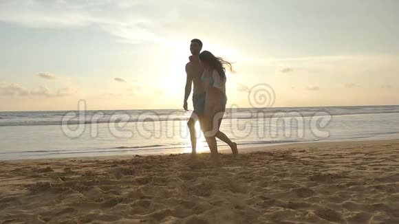 美丽而愉快的一对夫妇在日落时沿着海边散步快乐的男人和女人在海上视频的预览图
