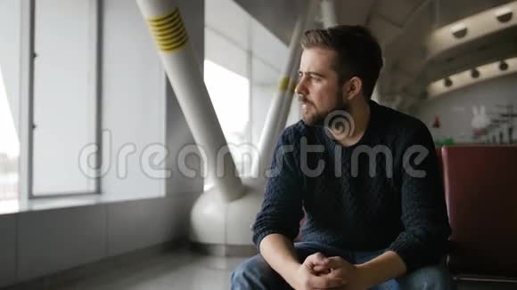 英俊的胡须男坐在机场等待出发视频的预览图