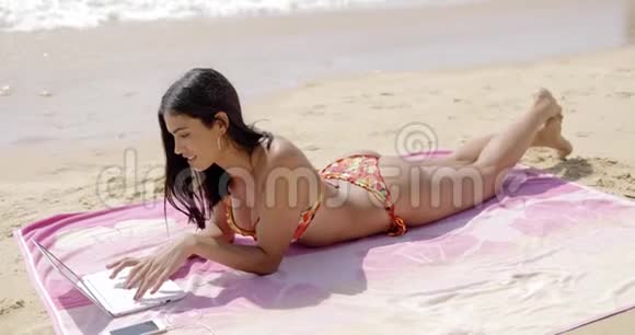 带笔记本电脑的快乐女人在沙滩上放松视频的预览图