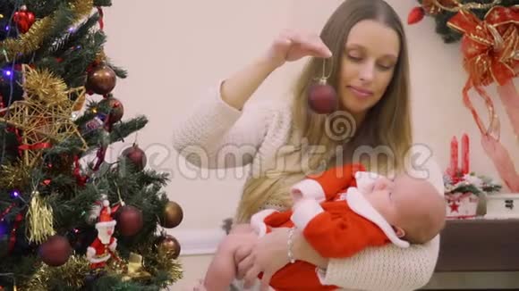 手里拿着女婴的年轻女子装饰圣诞树视频的预览图
