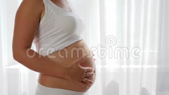 健康的营养孕妇端着玻璃牛奶慢动作地抚摸大肚子视频的预览图