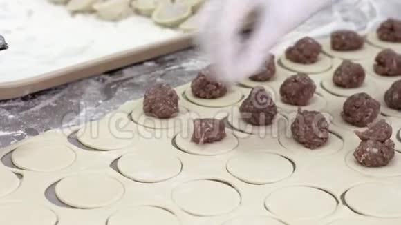 戴白手套的女工用面团包肉包饺子工厂视频的预览图