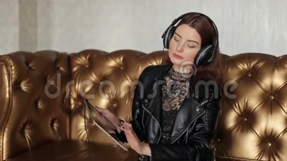戴着耳机的漂亮女孩坐在一张皮沙发上视频的预览图