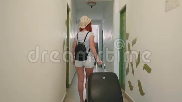 年轻快乐的女人带着手提箱进入她的酒店房间视频的预览图