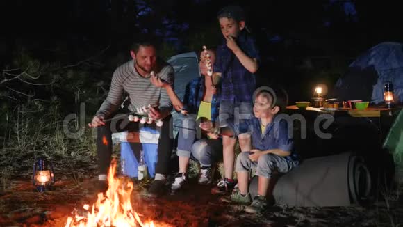 妈妈和爸爸带着孩子在露营地休息在篝火上烤热比带着孩子的父母带着孩子的小棉花糖视频的预览图