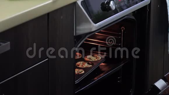 手拿热防护手套打开烤箱门带蛋糕和肉视频的预览图