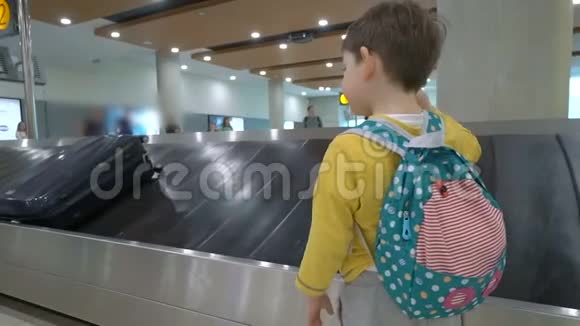 在机场候机楼到达休息室传送带等待行李的儿童视频的预览图