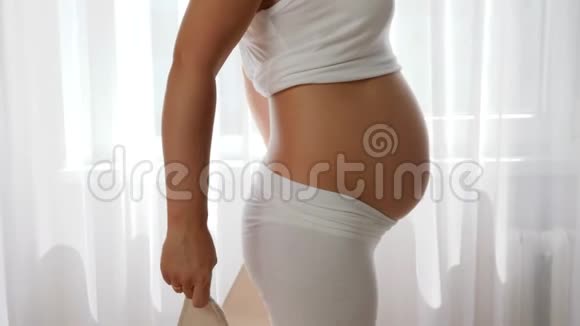 未来的母亲为孕妇收紧绷带缓慢地触摸大肚子视频的预览图