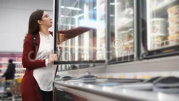 带背包的女人从超市的冰箱里挑选产品视频的预览图