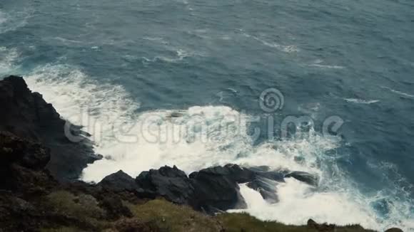 近景观海波浪与泡沫溅在岸边黑色岩石上视频的预览图