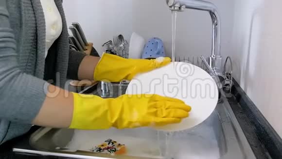 特写慢镜头视频年轻女子穿黄色乳胶手套在厨房洗碗视频的预览图