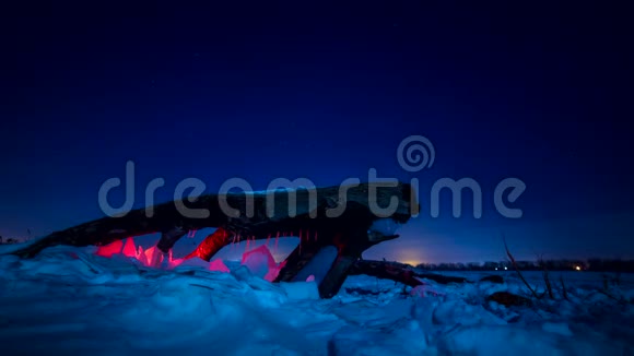 原木下的冰栅栏被红灯照亮地球在白雪覆盖的田野里旋转视频的预览图