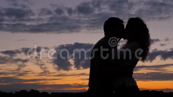 浪漫情侣剪影男人和女人在一起情人在夕阳下亲吻视频的预览图