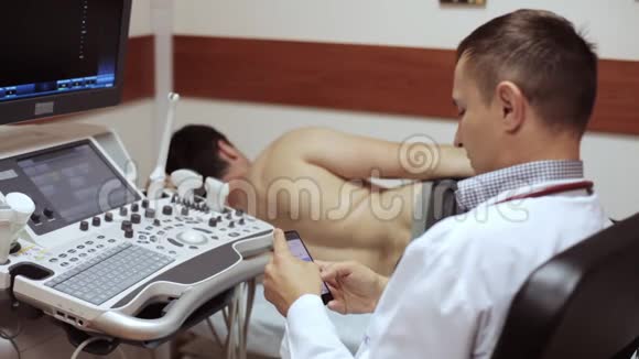 医生在病人躺着等待超声诊断时点击智能手机视频的预览图