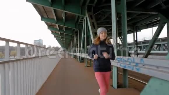 年轻女跑步者在工业桥上慢跑在城市做运动的女人视频的预览图