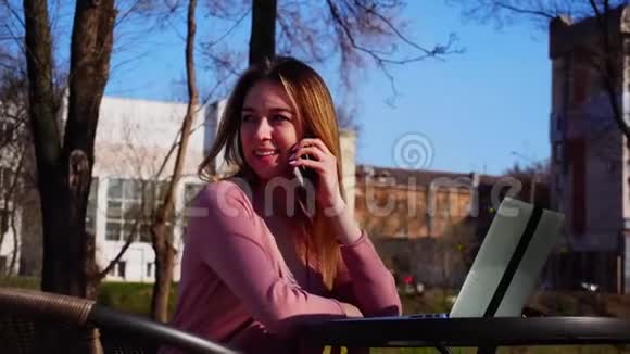 年轻女性通过智能手机和笔记本电脑在蓝天背景的新鲜空气中浏览视频的预览图