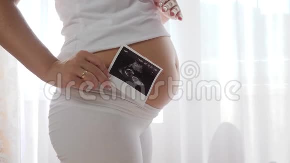 女性在缓慢运动中按摩她的大肚子并在腹部附近扫描未来的婴儿视频的预览图
