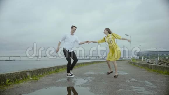 河岸上那对相爱的夫妇一起跳舞穿着漂亮黄色礼服的女人视频的预览图