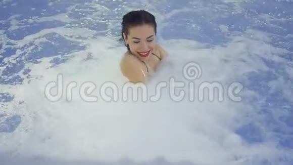 在游泳池的喷泉旁一个红唇的美丽的黑发女人放松视频的预览图