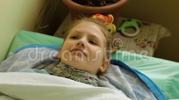 戴着围巾的微笑女孩躺在床上咳嗽视频的预览图