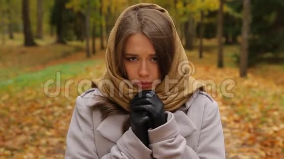 美丽的年轻女子感到寒冷准备在秋天的公园里哭泣视频的预览图
