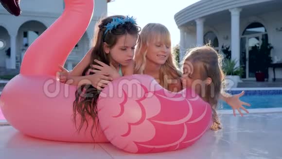 小女孩躺在游泳池附近的粉红色充气火烈鸟孩子们在暑假穿泳衣的名人被宠坏的富人视频的预览图