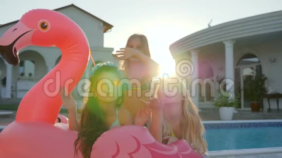 暑假的小女朋友可爱的女孩躺在游泳池附近的充气粉红火烈鸟上娇生惯养的富家子弟视频的预览图