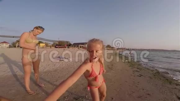 笑着的小女孩正在沙滩上玩耍和奔跑拿着相机视频的预览图