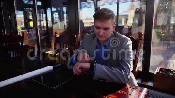 学生使用智能手表坐在咖啡馆与滚动项目平板电脑在桌子上视频的预览图