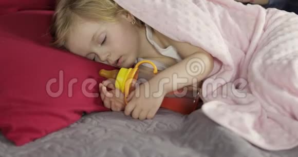 年轻的母亲在睡觉时照顾她的小宝贝女儿上床的女孩视频的预览图
