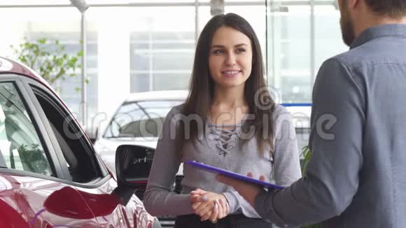 在汽车经销店和推销员谈话的年轻女子视频的预览图