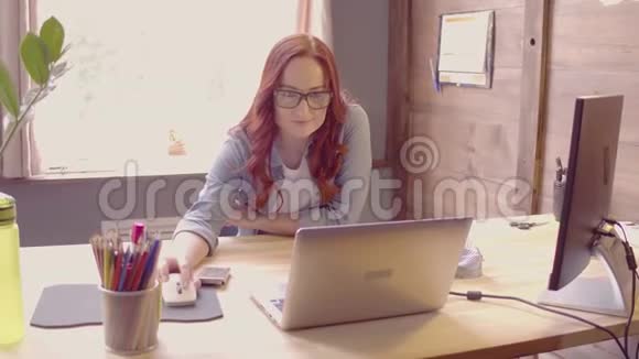 自由职业的年轻女性在笔记本电脑上工作在一张纸上做笔记视频的预览图