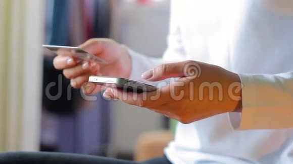 女人在智能手机上拿起信用卡号码高清镜头视频的预览图
