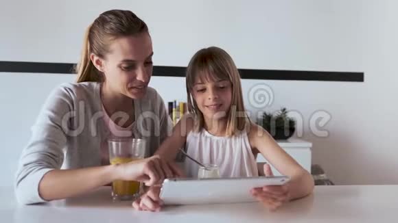 年轻漂亮的母亲和女儿在家里用数码平板电脑视频的预览图
