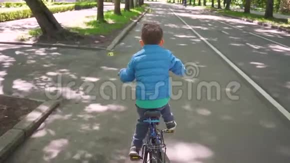 在城市公园里骑蓝色自行车的小男孩视频的预览图