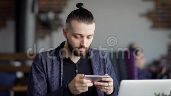 商人正在使用智能手机坐在咖啡馆里男经理在午餐时在桌旁聊天打字和视频的预览图