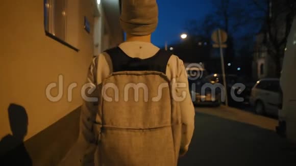 带背包的年轻人晚上拿着手机走在黑暗的大街上视频的预览图