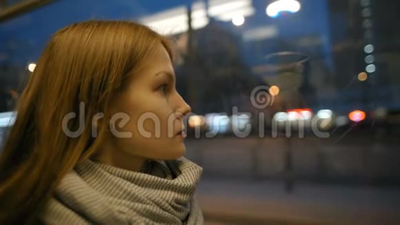 年轻的女士正穿着有轨电车向窗外眺望城市的夜生活视频的预览图