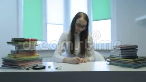 穿白衬衫的年轻老师在教室的书桌上写着一本书视频的预览图